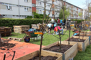 Menschen beim Gärtnern in der Stadt. In mehreren Hochbeeten wurden Bäume gepflanzt. Menschen beim Gärtnern in der Stadt. In mehreren Hochbeeten wurden Bäume gepflanzt.
